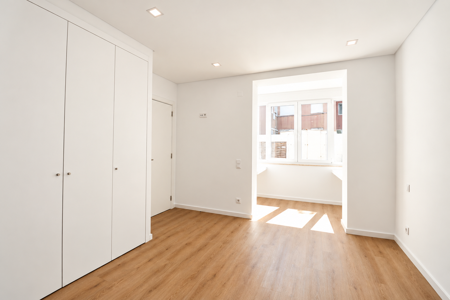 Quarto com roupeiro branco embutido e abertura para a marquise iluminada.