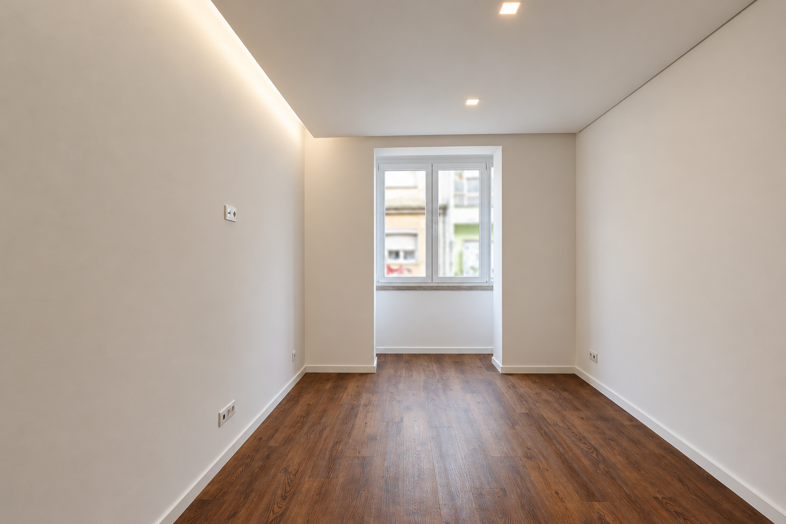 Living area with a two-panel window, indirect lighting along the ceiling and wood-effect flooring.