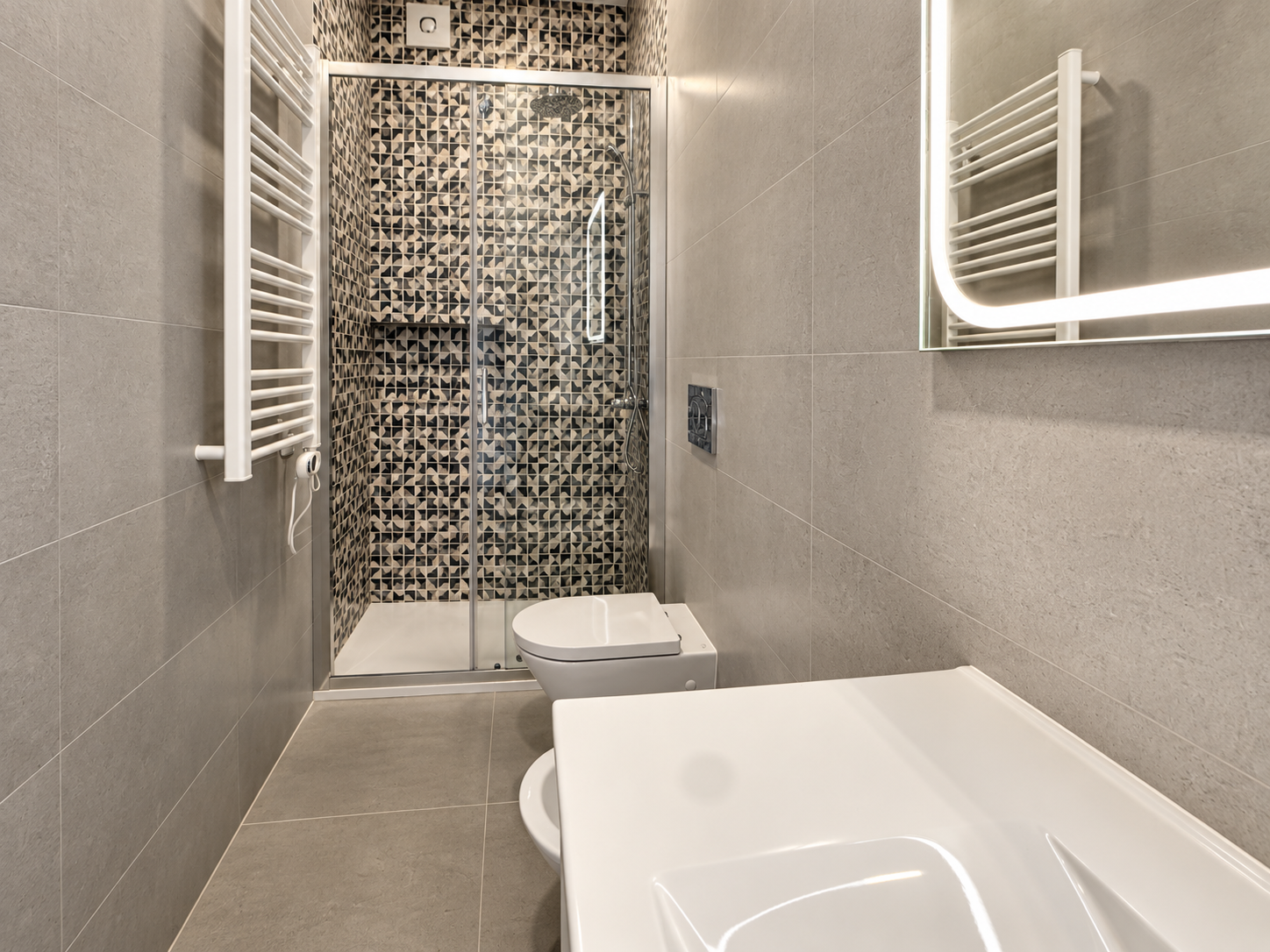 White washbasin and mosaic-tiled shower in Queijas