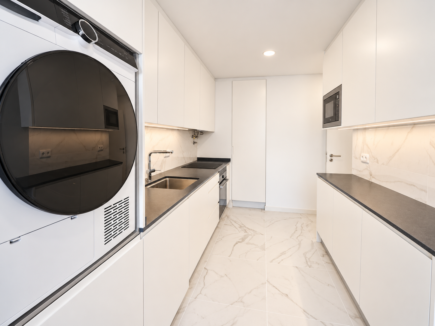 Parallel dark worktops between white cabinets and kitchen appliances